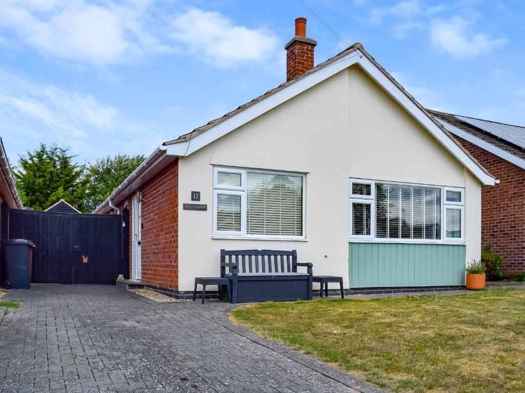 a white house with a bench in the driveway at Pinecote in Bottesford