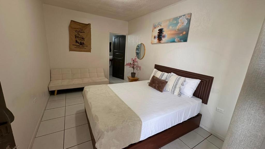 a bedroom with a large white bed and a couch at Basecamp Monteverde in Monteverde Costa Rica