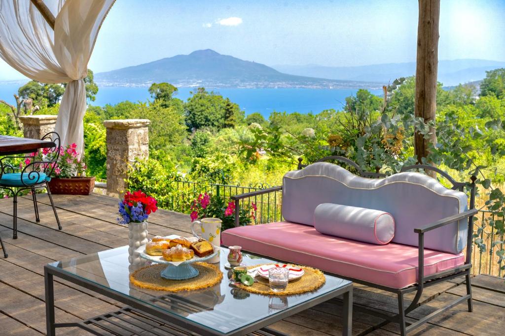 a patio with a pink couch and a glass table at La Dimora 4: Charm and Quiet in SantʼAgata sui Due Golfi