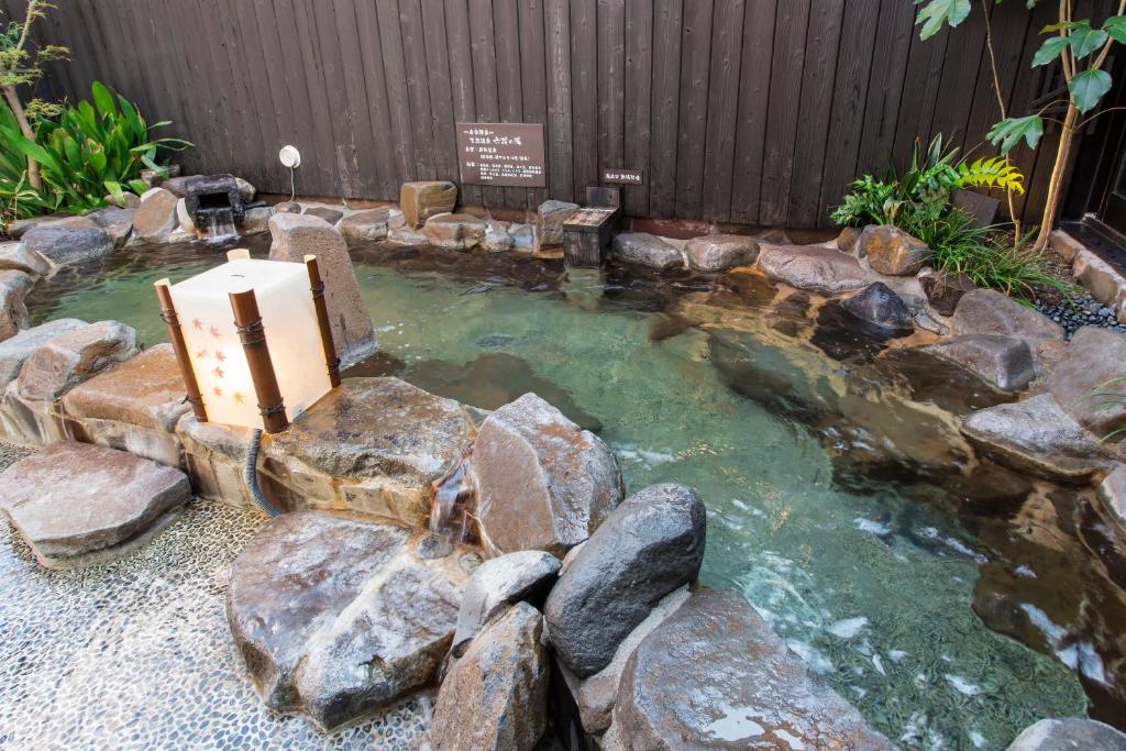 a pool of water with rocks in a backyard at Dormy Inn Kumamoto Natural Hot Spring in Kumamoto