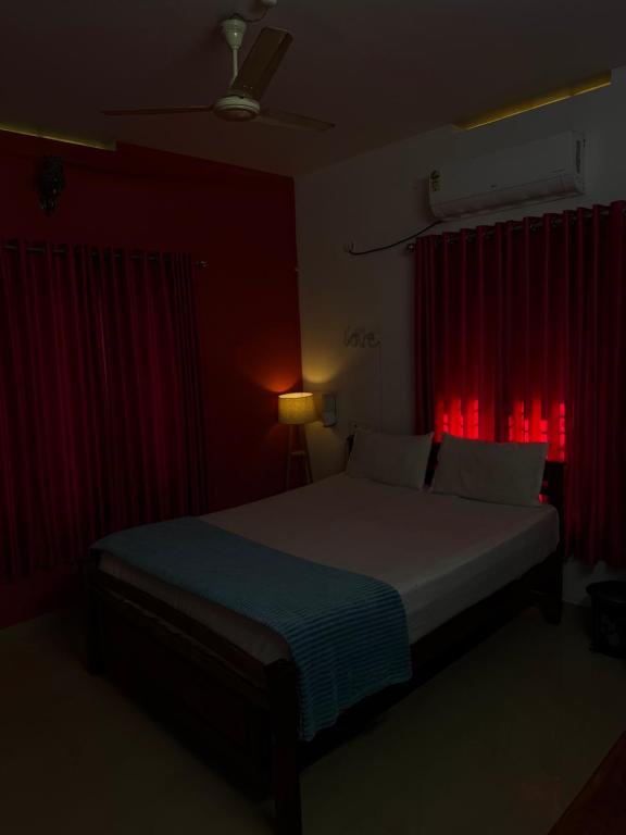 a bedroom with a bed with a red curtain at Mud apples stay in Varkala