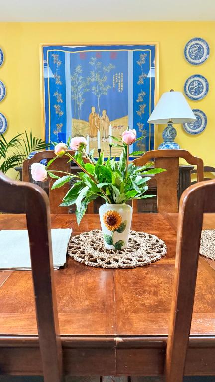 a dining room table with a vase with flowers on it at River Views, Private Fishing & 9 min Train to York in Ulleskelf