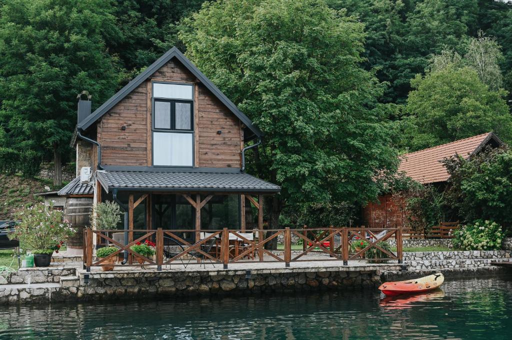 a house on the water with a boat in front of it at Vikendica Family in Gojsalica
