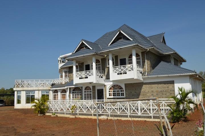 a large white house with a balcony on top of it at Balmoral Palace Kisumu in Kisumu International Airport