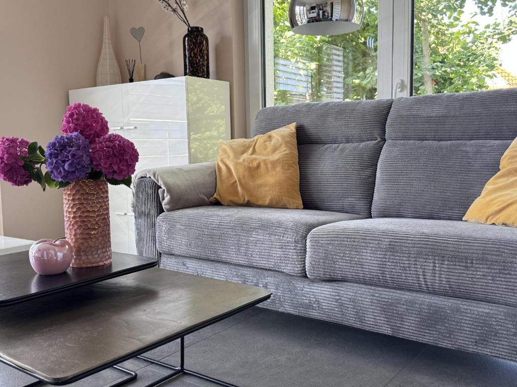 a living room with a couch and a table with flowers at Guetsel-Lodge - Δ in Gütersloh