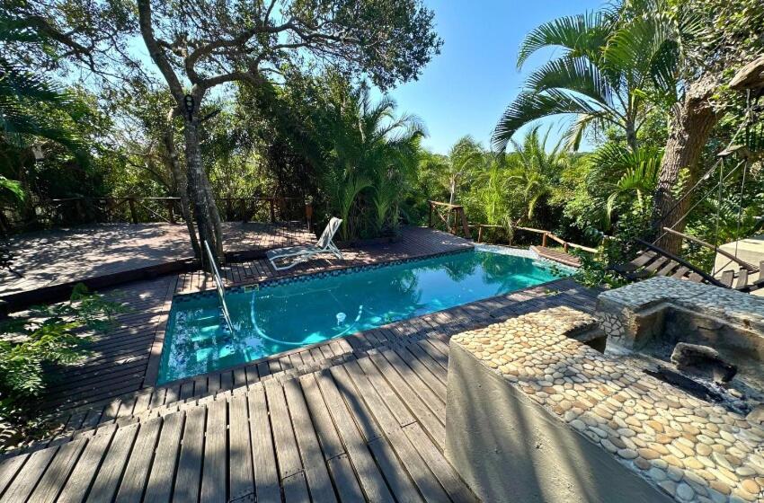 a swimming pool on a wooden deck next to a resort at Baleia Azul 24 in Ponta Mamoli