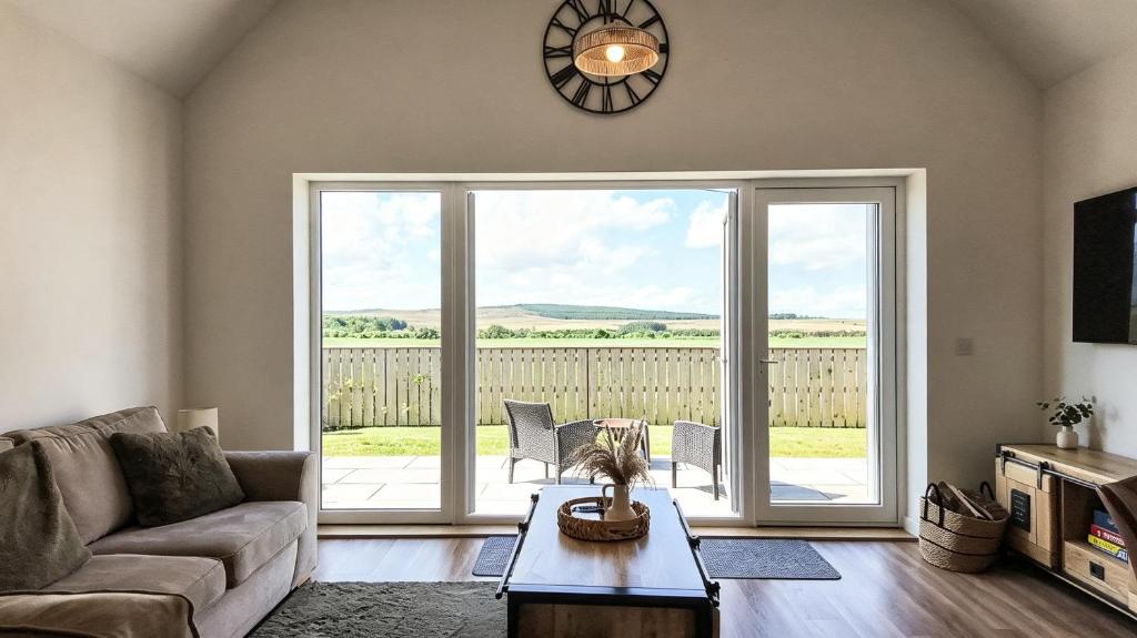 a living room with a couch and a large sliding glass door at Birch Tree Lodge - Luxurious Lodge on the NC500 by Thrumster Lodges in Wick