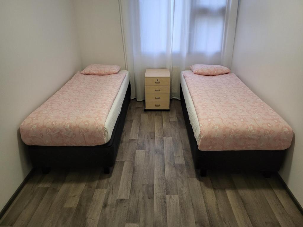 two beds in a small room with wooden floors at Private bedroom in Shared Apartment in Hämeenlinna