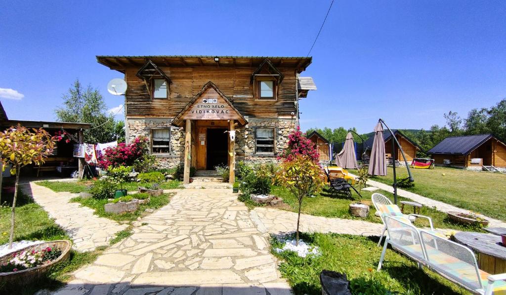 a small wooden house with a pathway in a yard at Vidikovac Uvac in Družiniće