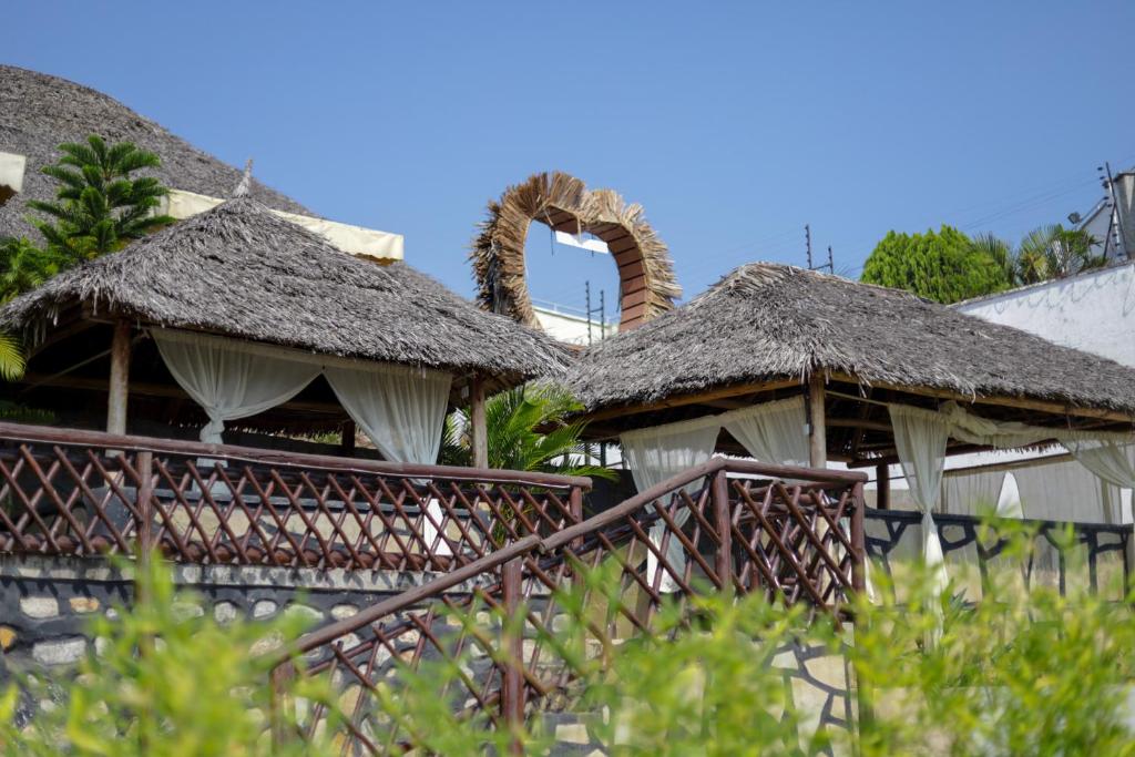 two huts with thatched roofs in a resort at Sky Beach Resort in Kisumu