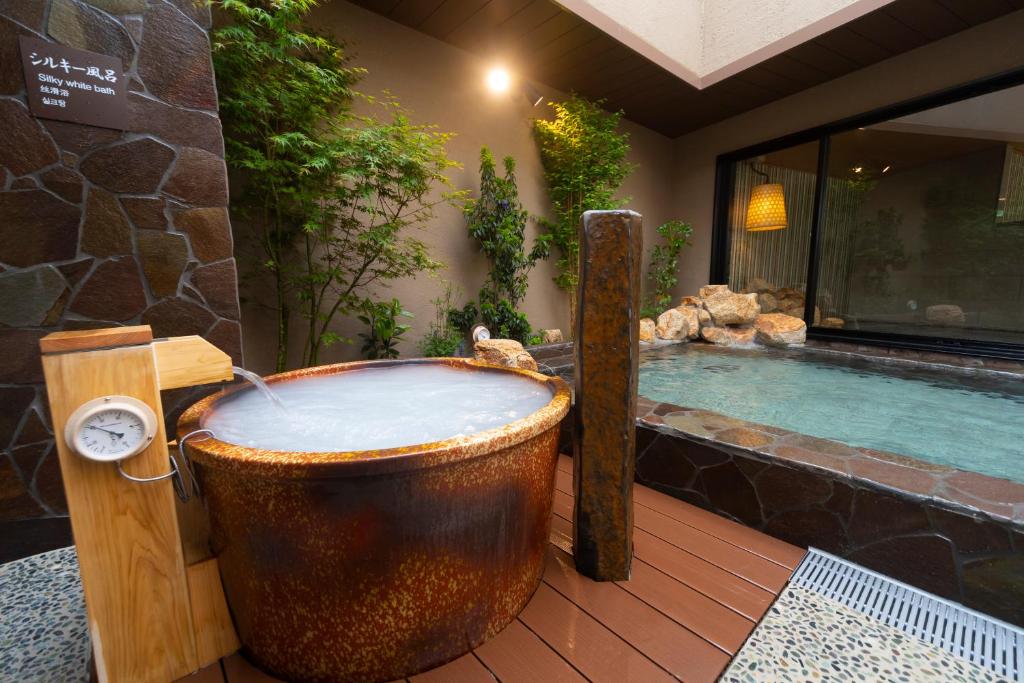 a large wooden bath tub sitting next to a swimming pool at Dormy Inn Oita in Oita