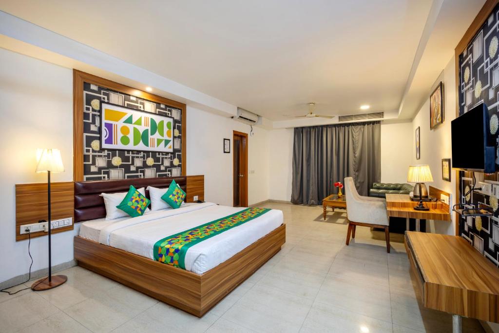 a bedroom with a bed and a desk and a television at Treebo Parth Paradise in Ghaziabad