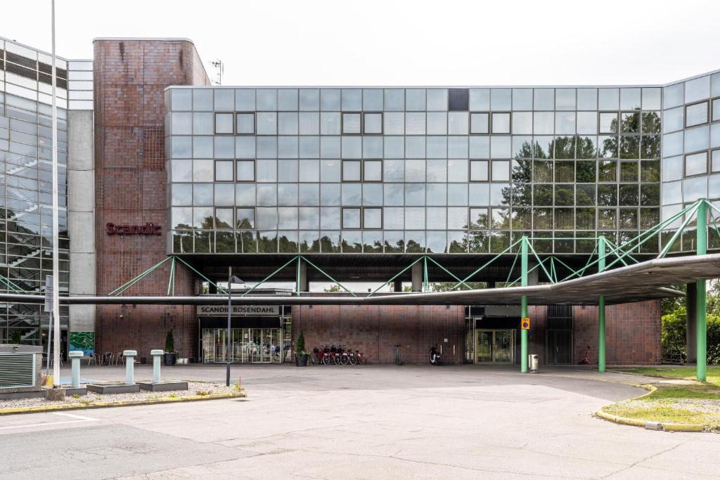 a large glass building with a parking lot in front of it at Scandic Rosendahl in Tampere