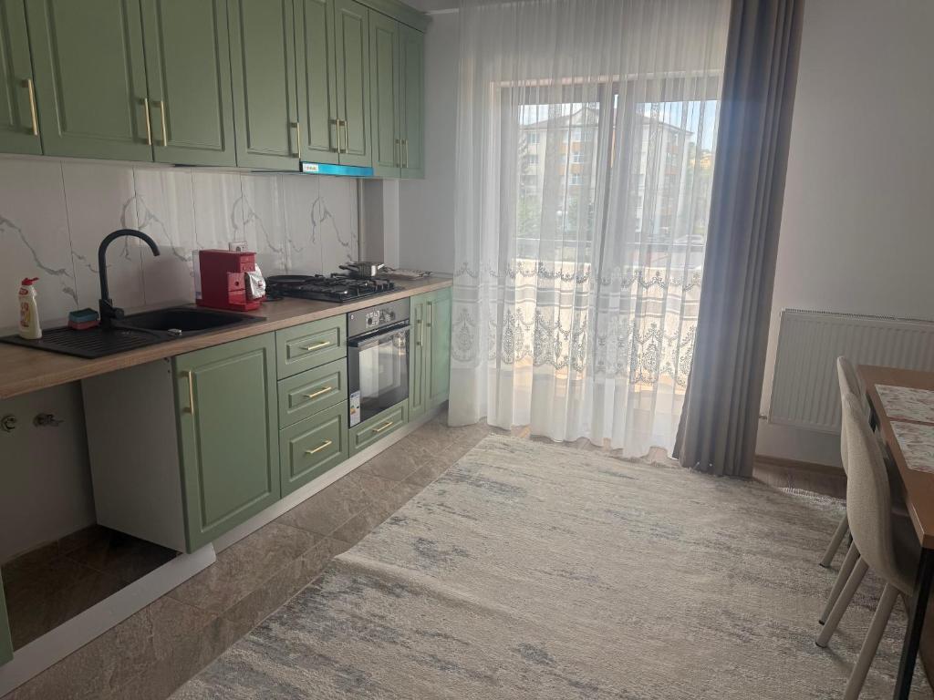 a kitchen with green cabinets and a window at Eli house in Târgu Neamț