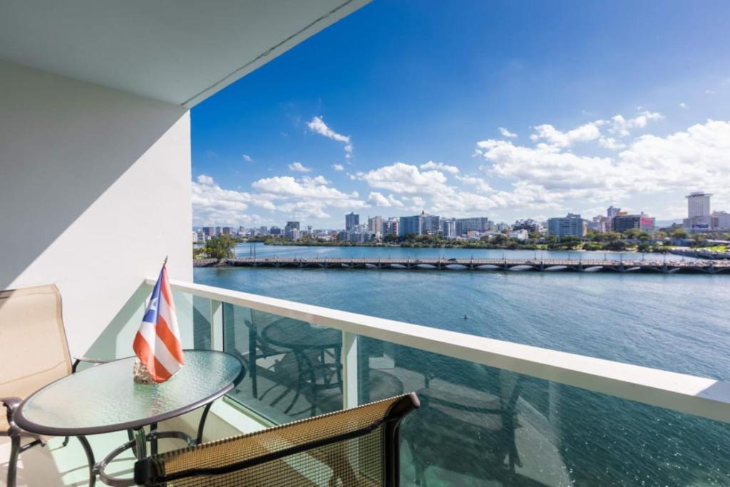 a balcony with a table and chairs and a view of the water at Premier Ocean Lagoon Studio · Condado with Pool in San Juan