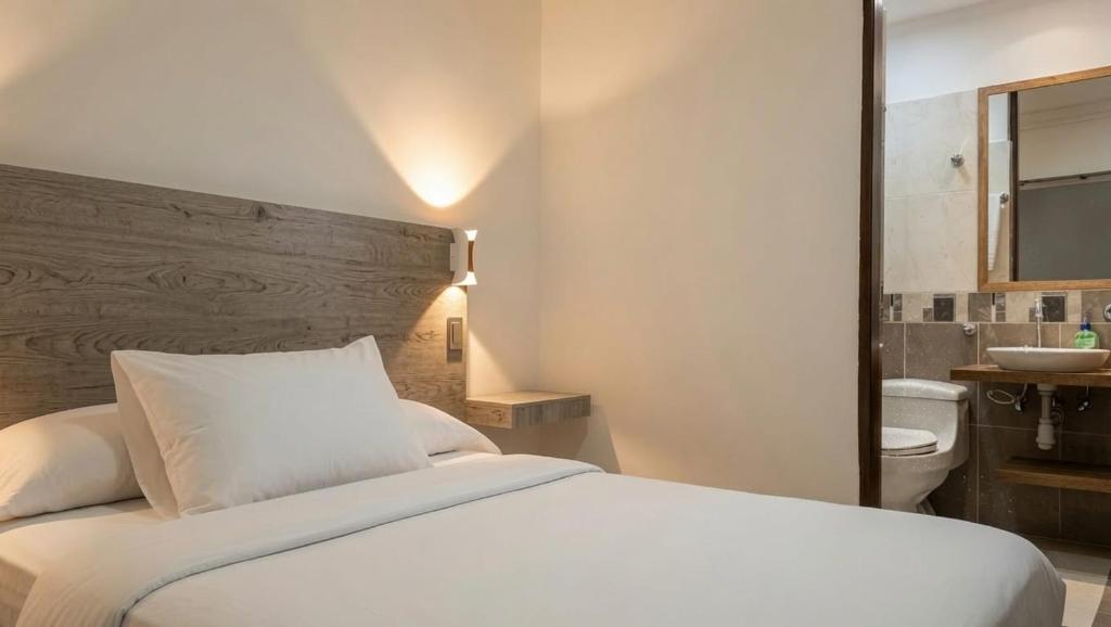 a bedroom with a white bed and a bathroom at Hotel Barbacoa Apartadó in Apartadó