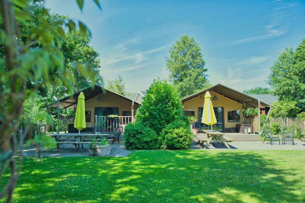 a park with tables and umbrellas in front of a building at Boeren glamping De Ruif De zilverberk in Stoutenburg