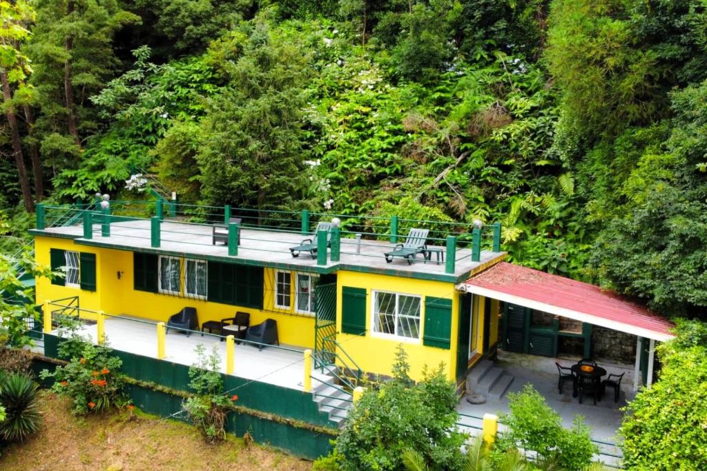 a yellow house with a red roof in the forest at Casa Varanda das Furnas in Furnas