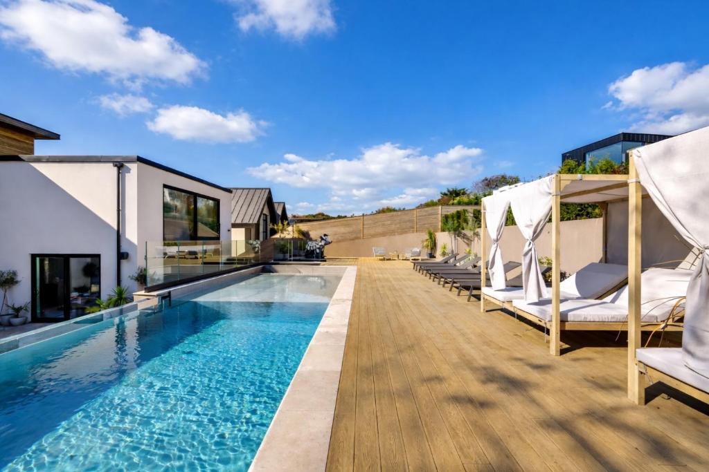 a swimming pool with chaise lounge chairs next to a house at Designer Haus - Pool - Sea Views - 7BR - Sleeps 14 in Brighton & Hove
