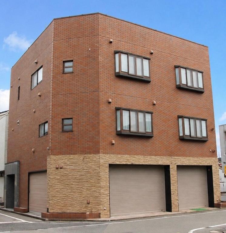 a red brick building with four garage doors at Tokyo Grand House in Akishima