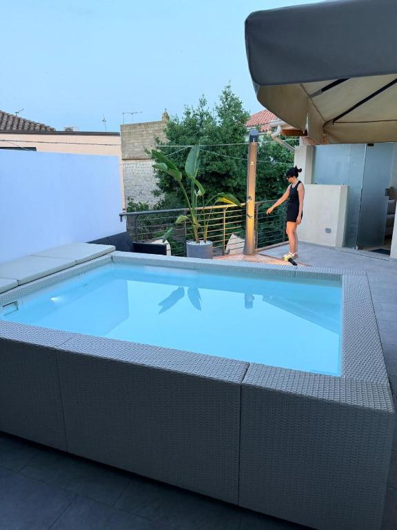 a person is standing next to a swimming pool at Tortolì Old Town - Sardiniarooms in Tortolì