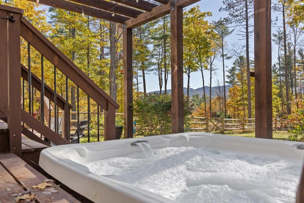 a bath tub on a deck with a view of trees at Luxury Retreat, Views, Near Whiteface, Lake Placid in Jay