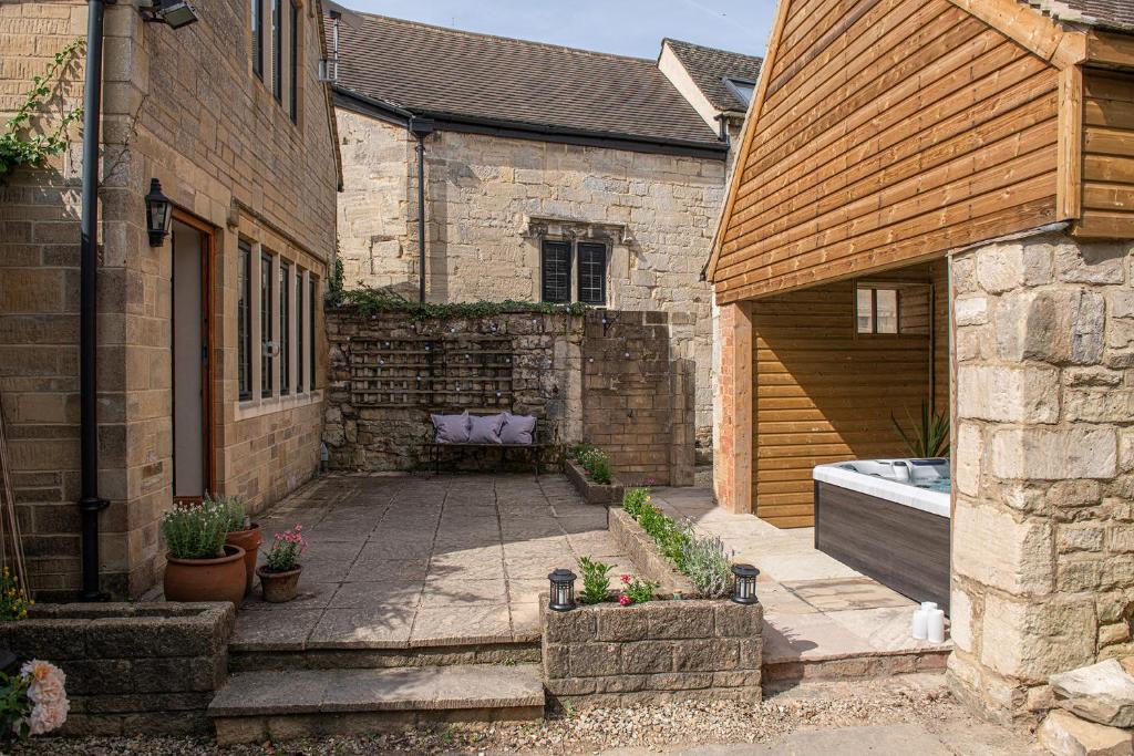 a courtyard of a house with a bench in it at Serenity in Painswick