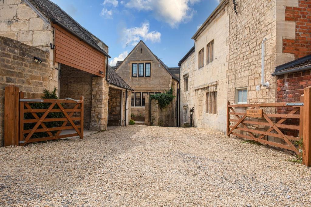an alley between two buildings with a wooden gate at Tranquility House in Painswick