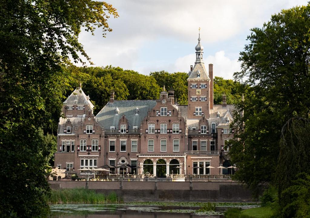 a large building with a tower on top of a river at Landgoed Duin & Kruidberg in Santpoort-Noord