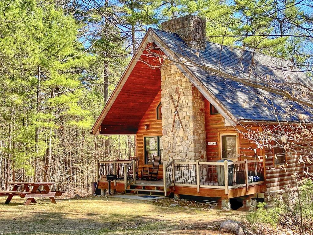 a log cabin in the woods with a picnic table at Luxury ADK Retreat Near Whiteface, Lake Placid in Jay