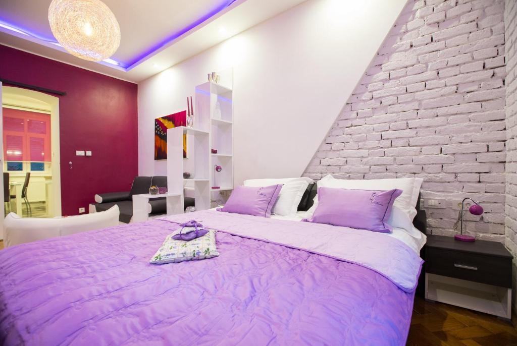 a bedroom with a purple bed with a brick wall at Apartment Center Four stars in Zagreb