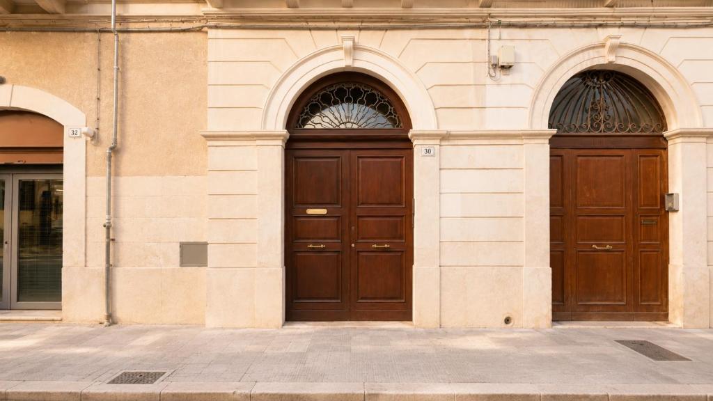 two brown doors on a building with two arches at The Suite - Trani centro in Trani