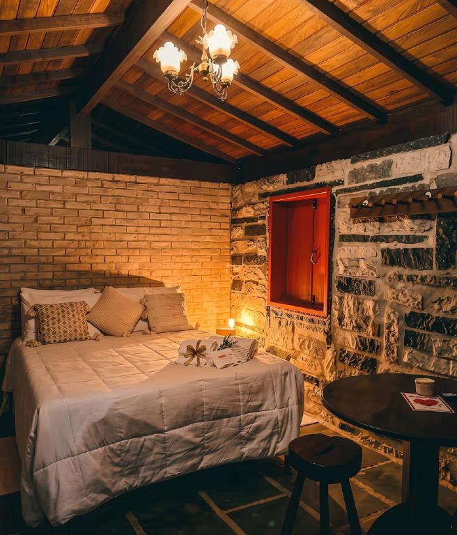 a bedroom with a large bed in a brick wall at Chalé Carrara, um Refúgio de Pedra na Mata - Chalés Flor dos Manacás in Santa Teresa
