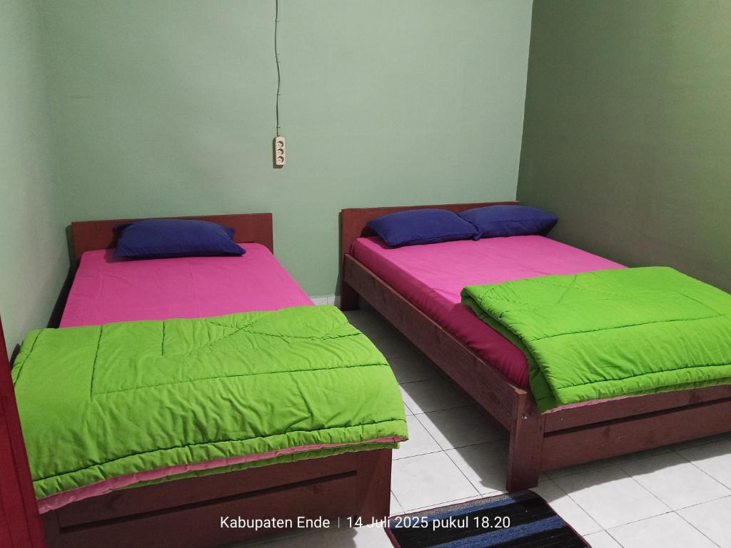 two beds with green and pink covers in a room at Kelimutu Lodge in Kelimutu