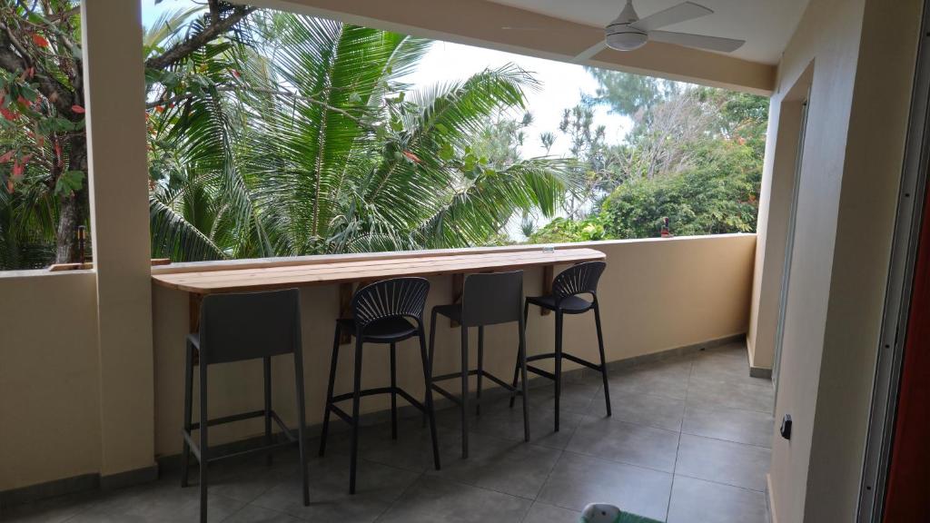 a balcony with a bar with four stools at le Chant des vagues 1 in Saint-Philippe