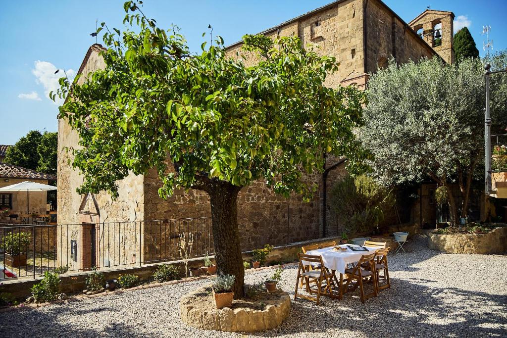 a table and a tree in front of a building at CasaBianchini Charming Home Val d'Orcia in Monticchiello