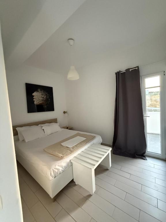 a white bedroom with a bed and a window at Klouvas apartment in Klouvas
