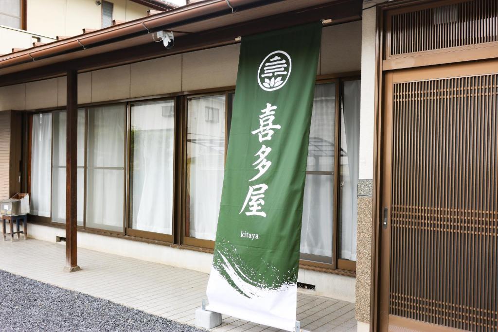 a green and white banner in front of a building at 民泊 Vacation rental "Tajimi-jyuku Kitaya" Base for trips to Ghibli Park,Tsumago-juku,Magome-juku in Tajimi