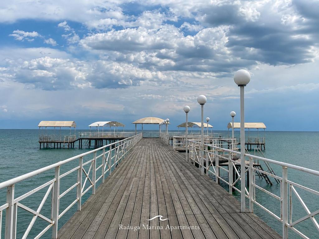 a wooden pier with umbrellas on the water at РАДУГА Иссык-Куль in Chon-Sary-Oy