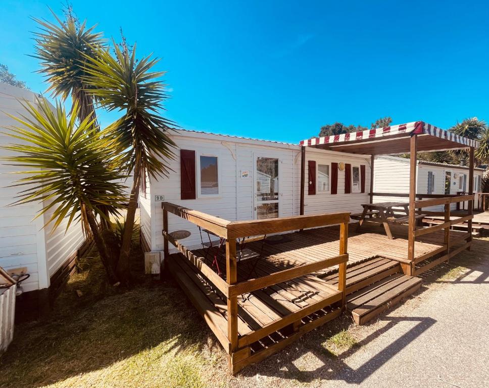 a mobile home with a deck and a palm tree at Vickys Walls Bungalow in Pataias