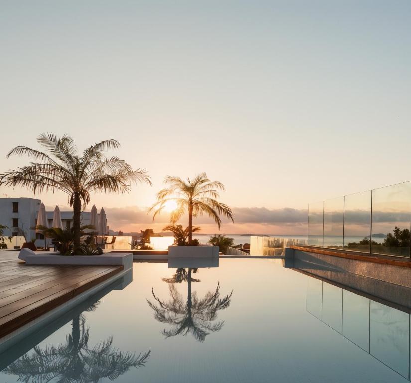 ein Pool auf dem Dach eines Gebäudes mit Palmen in der Unterkunft Nativo Hotel Ibiza by NCalma Hotels in Santa Eulària des Riu