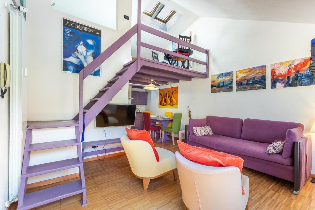 a living room with a purple couch and a spiral staircase at Hostdomus - Purple Apartment in Cesana Torinese
