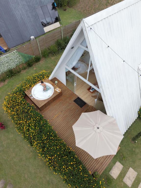 a man in a bath tub in a backyard with an umbrella at Cabana Branca luxo in Teresópolis