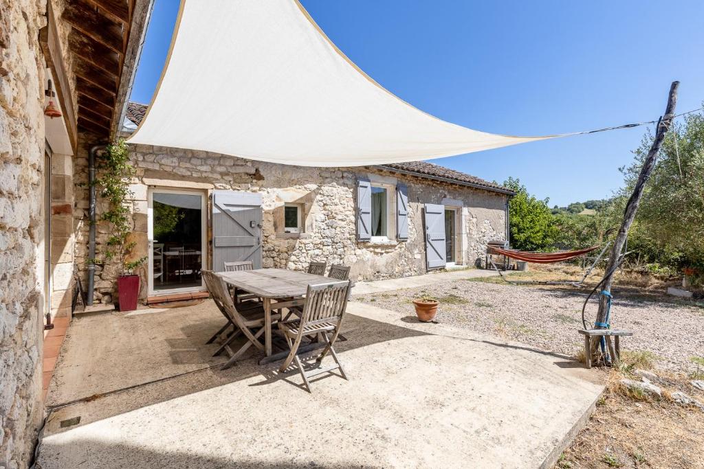 a table and chairs in front of a stone house at Maison de Charme en Pleine Nature in Bournazel