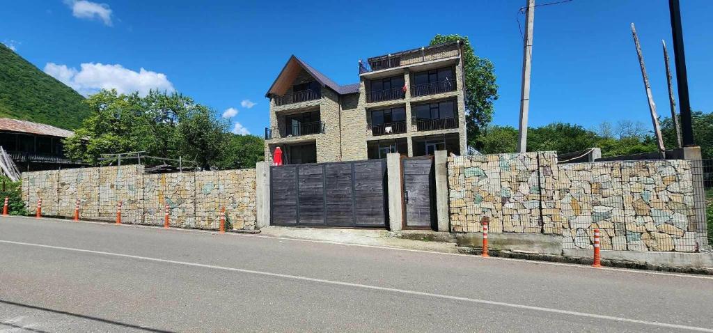 a stone wall with a building behind a fence at Villa Okatse in Zeda-Gordi