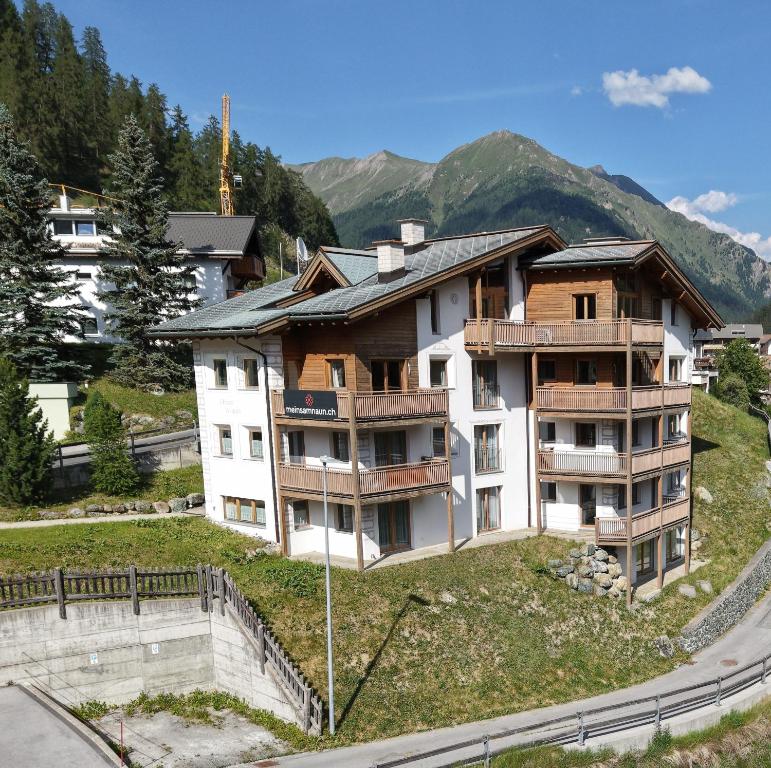 an apartment building on a hill with mountains in the background at Chasa Vaidum by MEIN SAMNAUN - MOUNTAIN HOMES in Samnaun