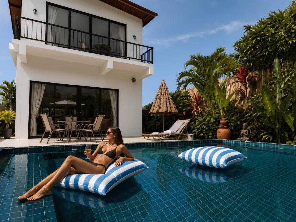 a woman in a bikini sitting on a raft in a swimming pool at Beachside Villa in Ko Phangan