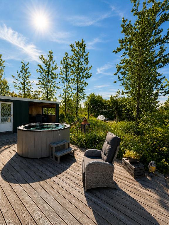 a patio with a hot tub and a chair on a deck at Hjartarstaðir Private Country Retreat with Hot Tub in Hagi