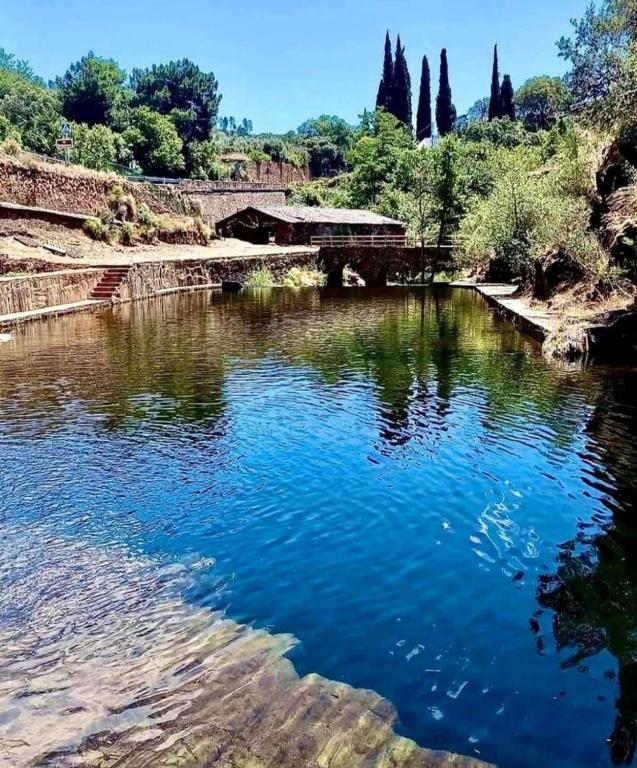 a body of water with a bridge and trees at Apartamentos Rurales El Prado in Pinofranqueado