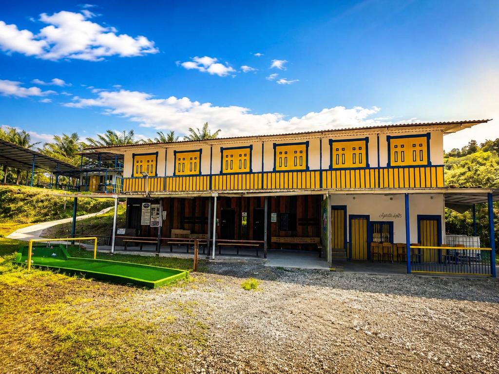 ein großes gelbes Gebäude mit gelben Fenstern und einem Spielplatz in der Unterkunft Salento River Hotel in Salento